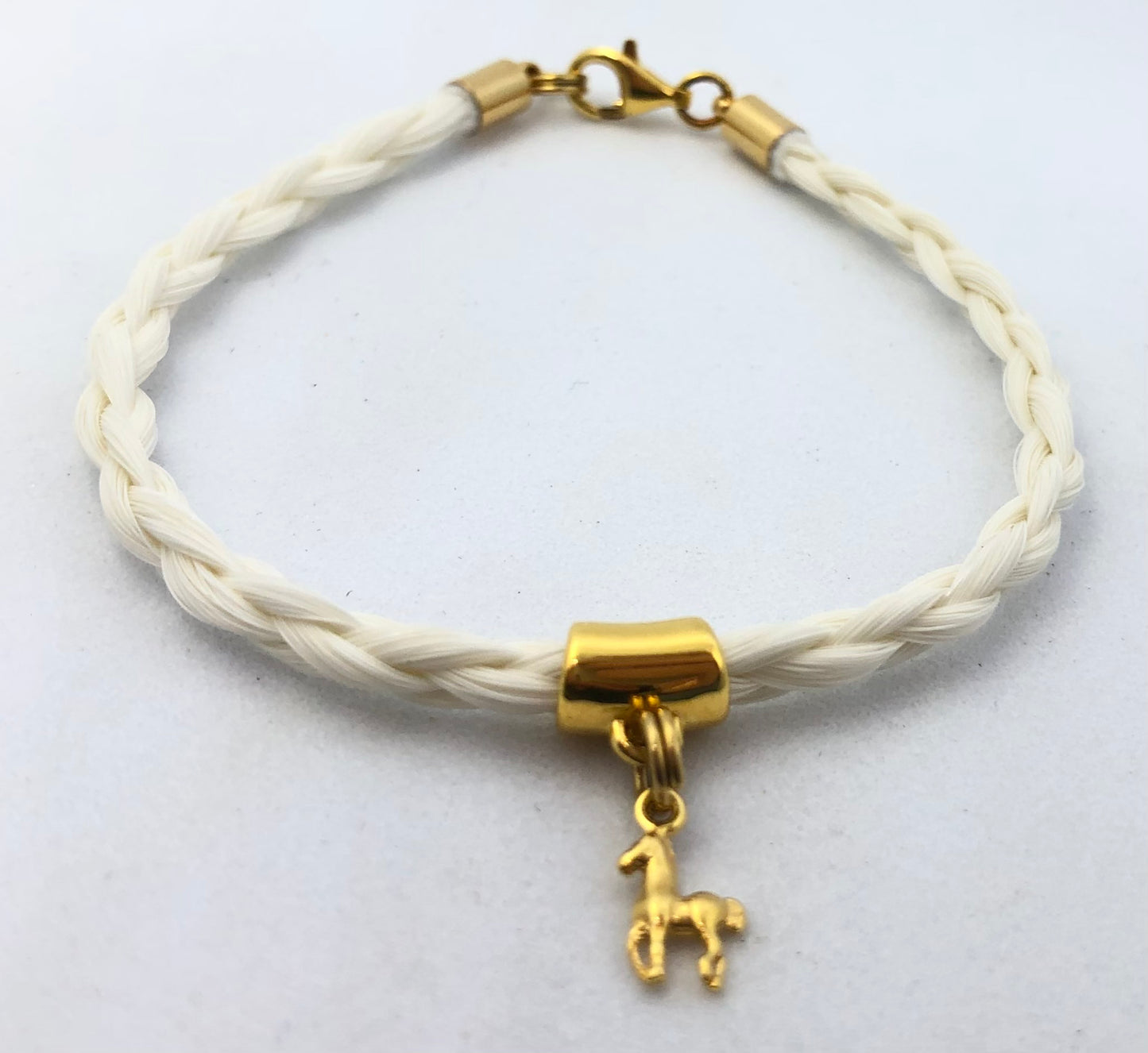 bracelet en crin de cheval avec tresse ronde et breloque cheval en acier inoxydable doré ou argenté.