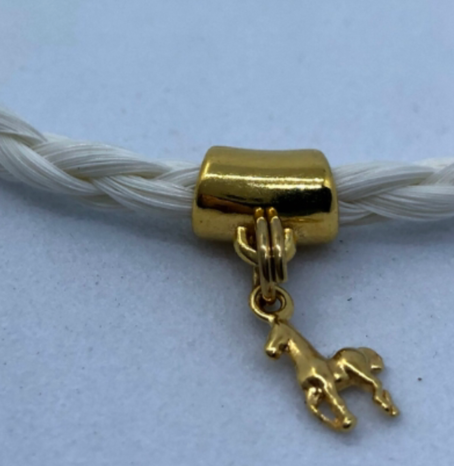 bracelet en crin de cheval avec tresse ronde et breloque cheval en acier inoxydable doré ou argenté.